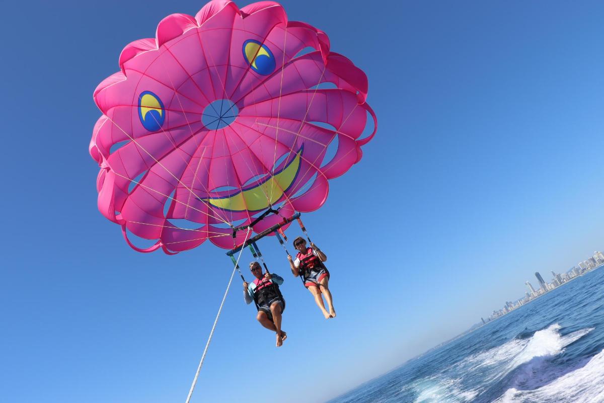 a person is hanging from a large pink kite