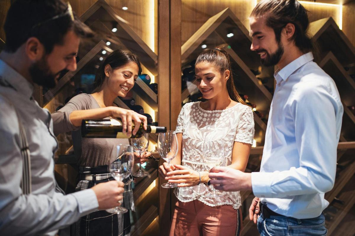 a group of people drinking wine in a wine cellar