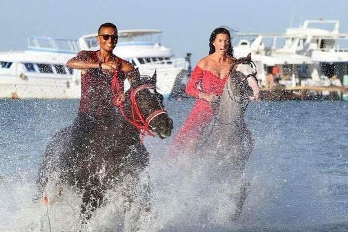 Un hombre y una mujer paseando a caballo en el agua