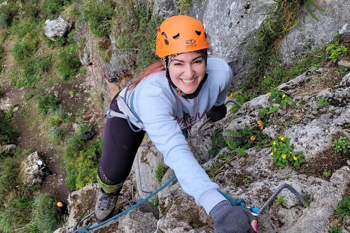 Una mujer con un casco naranja escalando una pared de roca