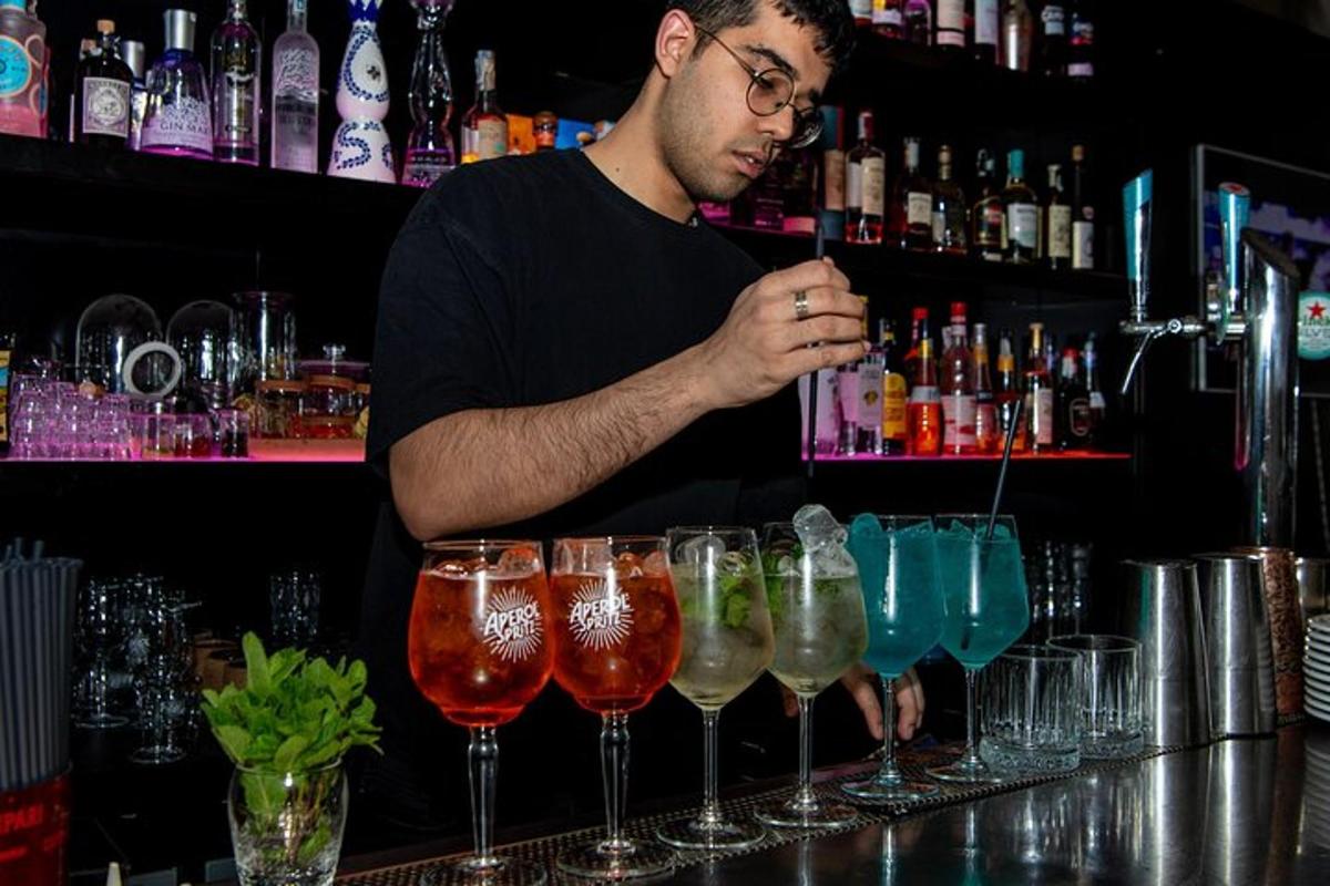 un uomo in piedi dietro un bar con una fila di bicchieri di vino