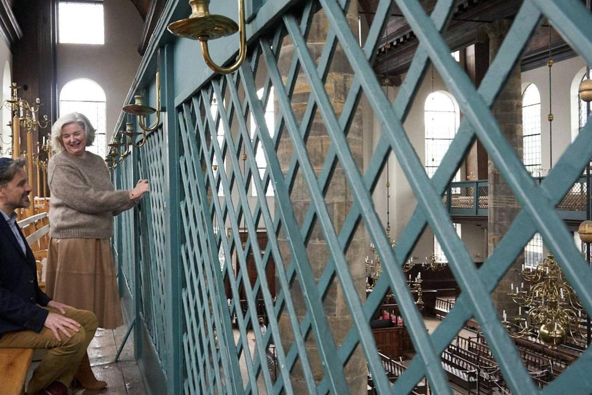 a woman standing next to a fence in a room