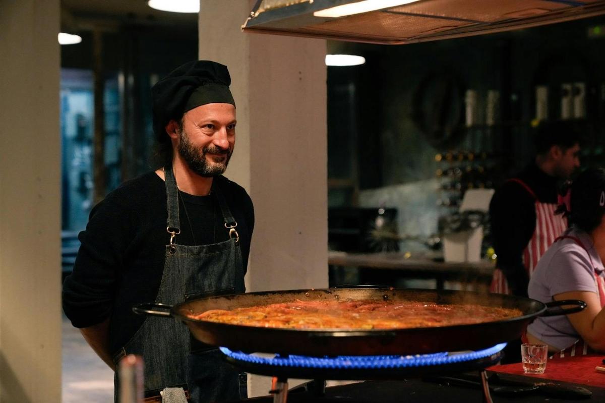 muž stojící v kuchyni s velkou pizzou