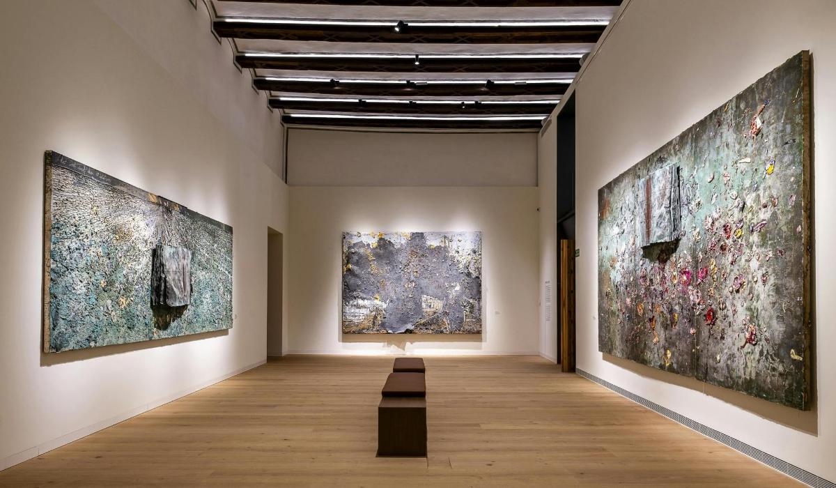 Una galería con tres grandes cuadros en las paredes.