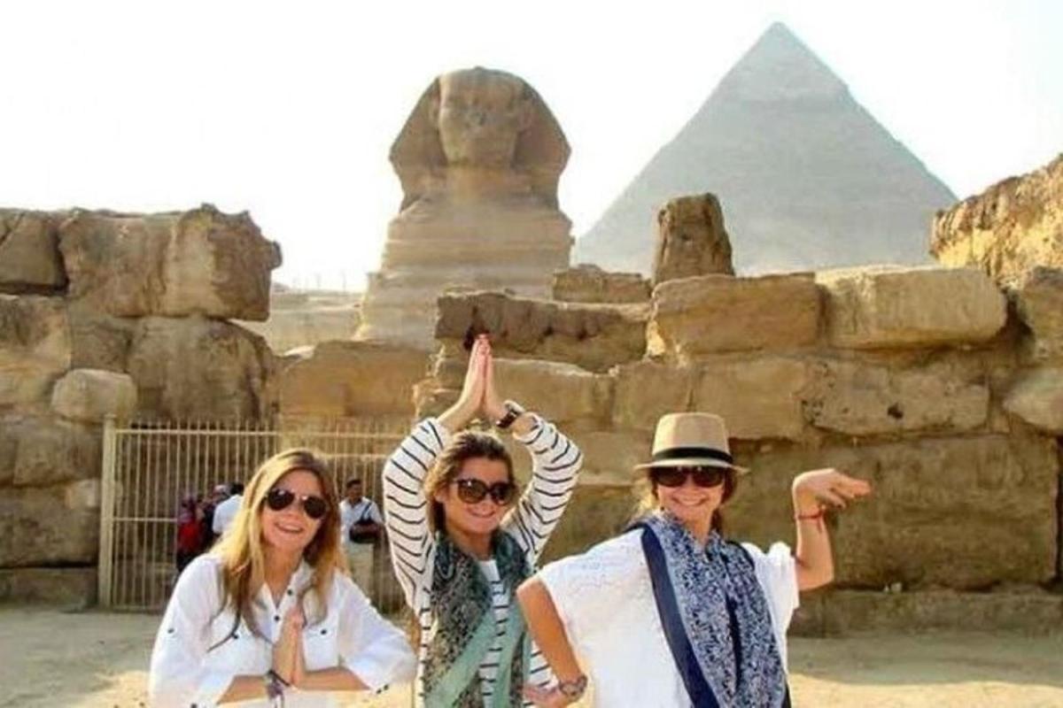 tři ženy pózující před pyramidami