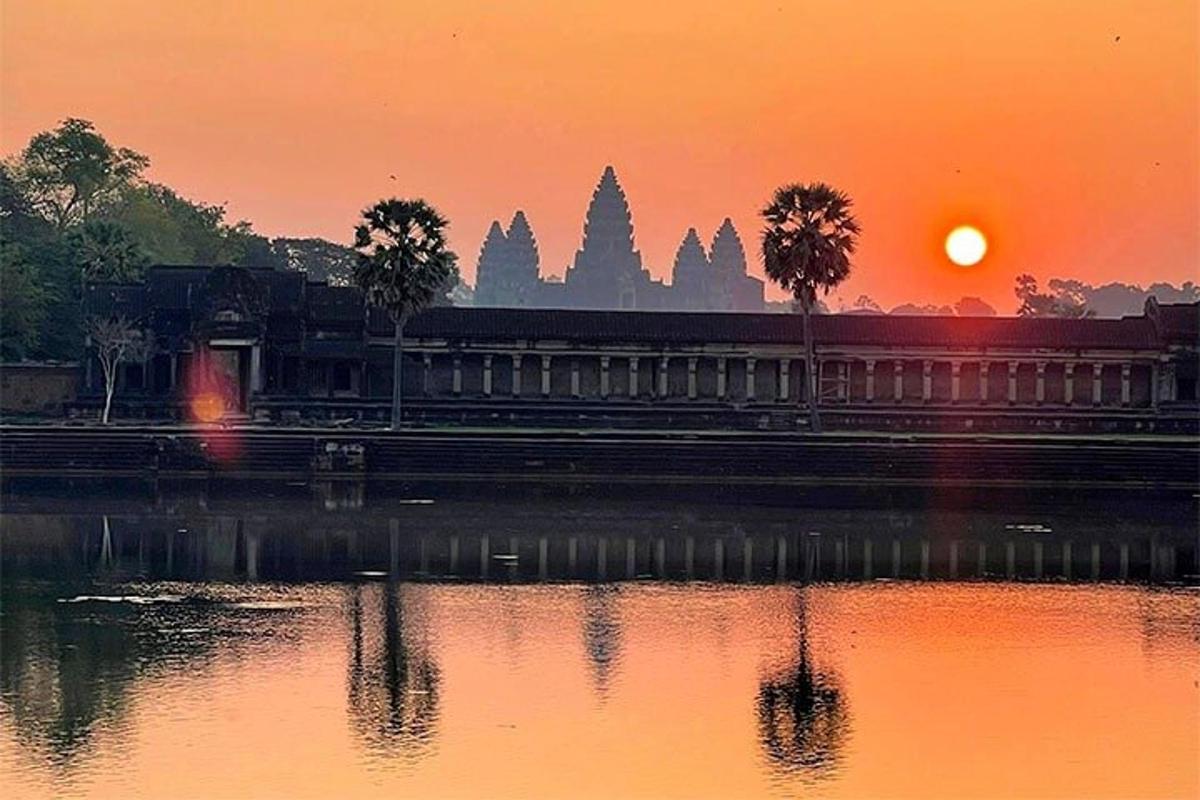 um pôr do sol em frente a um edifício e um corpo d'água