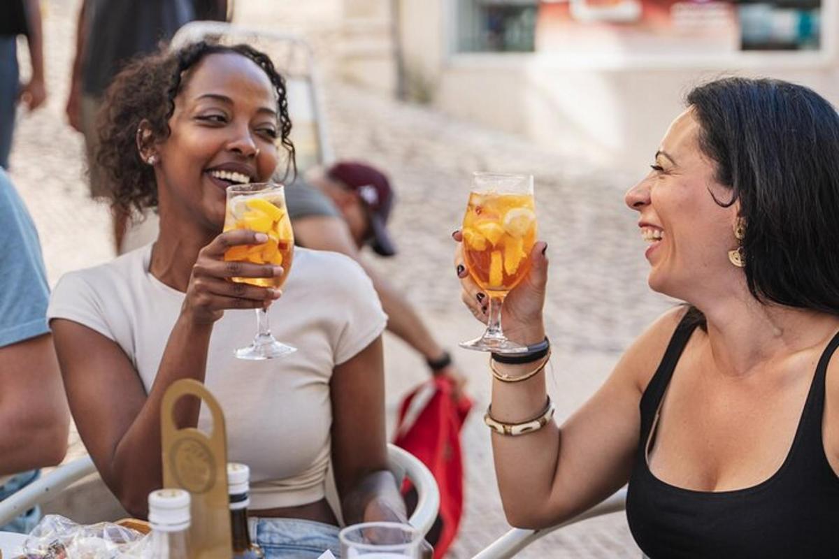 dues dones assegudes a una taula sostenint copes de vi