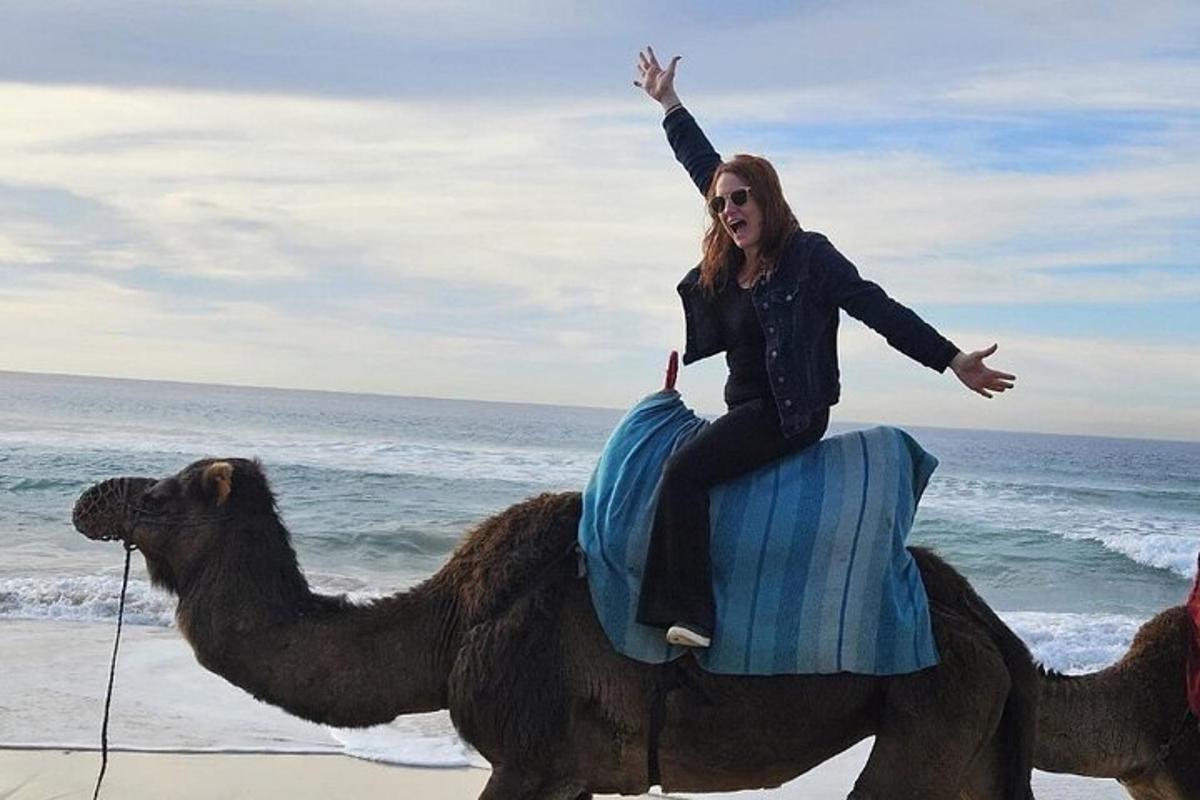 eine Frau, die auf einem Kamel am Strand reitet