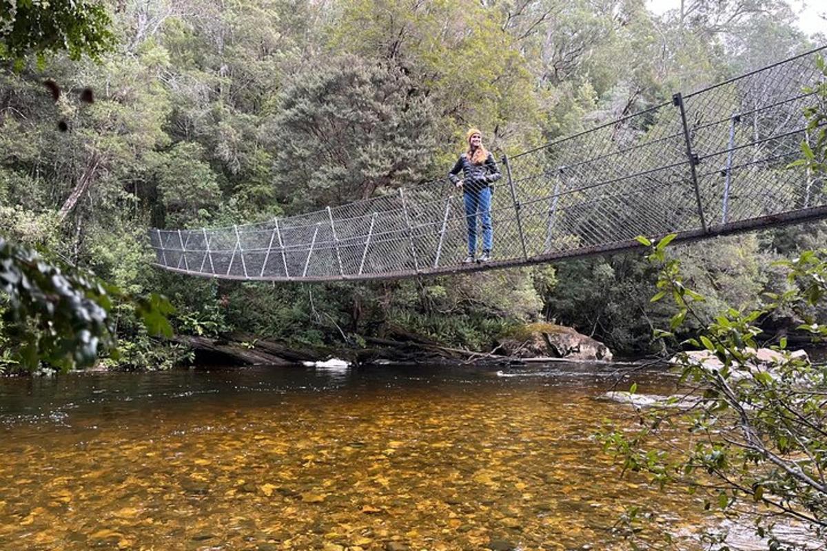 moteris, stovinti ant pakabinamojo tilto virš upės