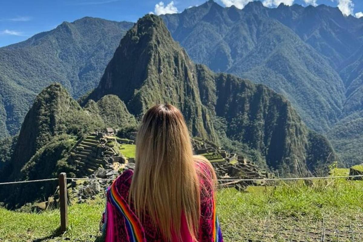 una donna seduta su una staccionata che guarda una montagna