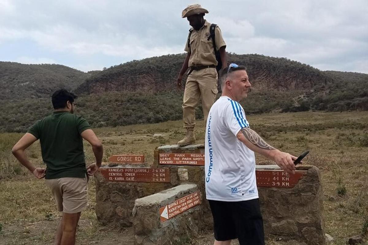 Dos hombres de pie sobre un cartel con una estatua encima