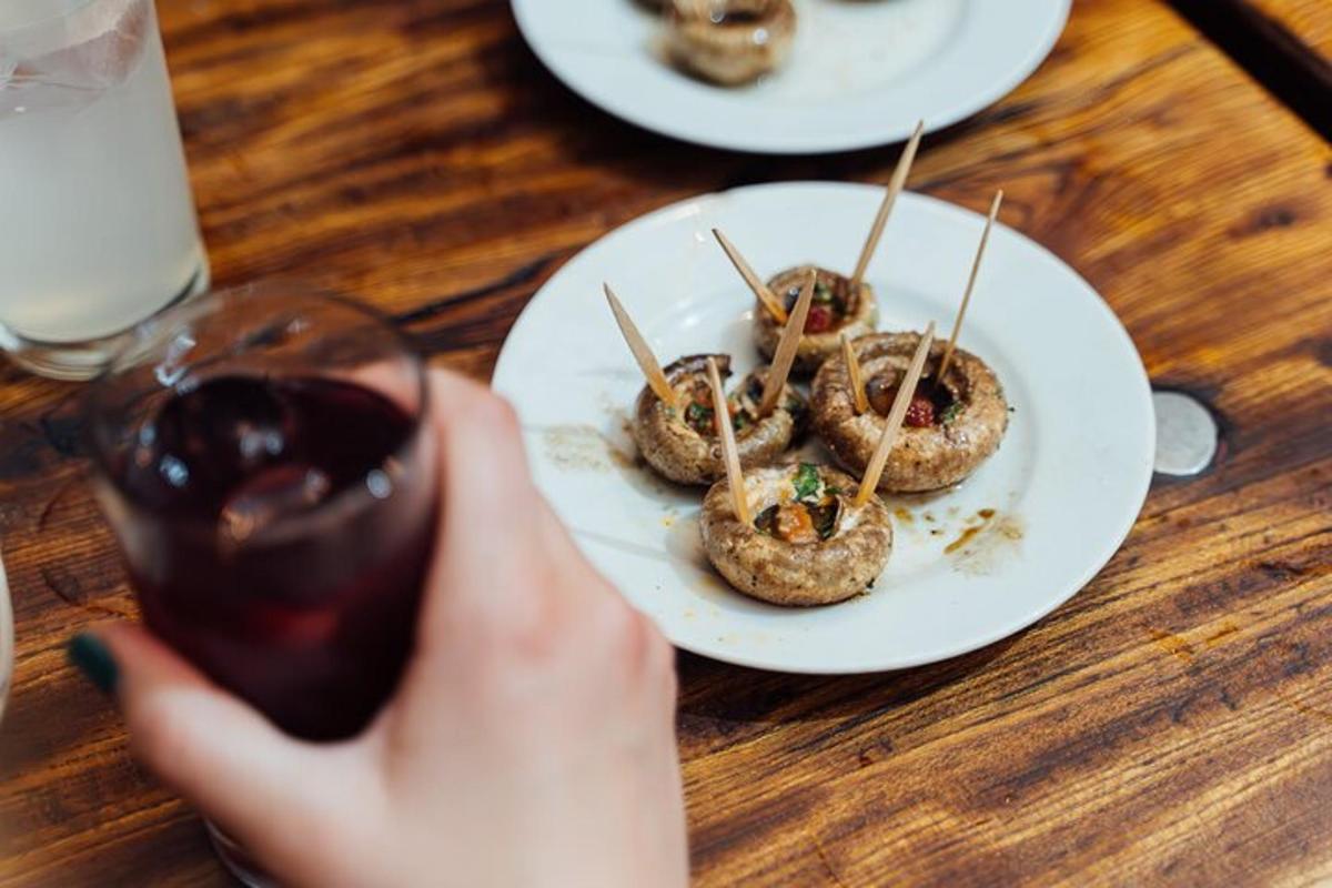 una persona sosteniendo una copa de vino y un plato de comida