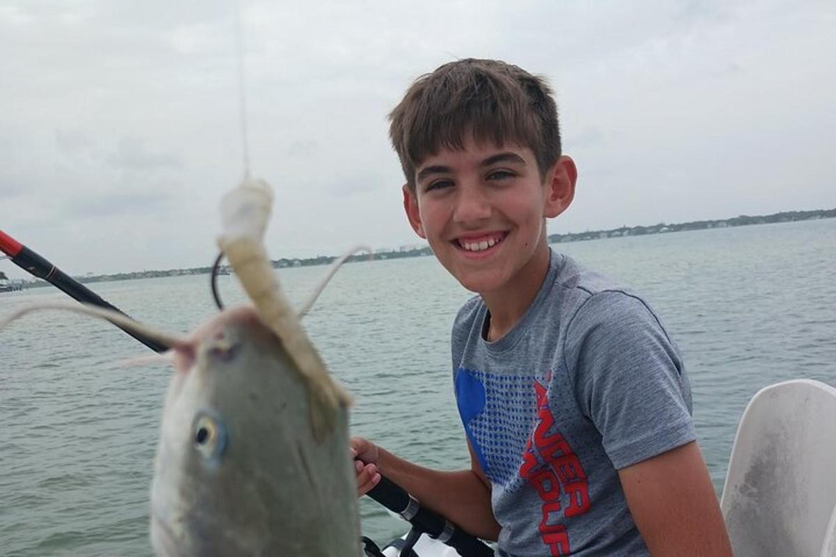 seorang budak lelaki di atas bot dengan seekor ikan