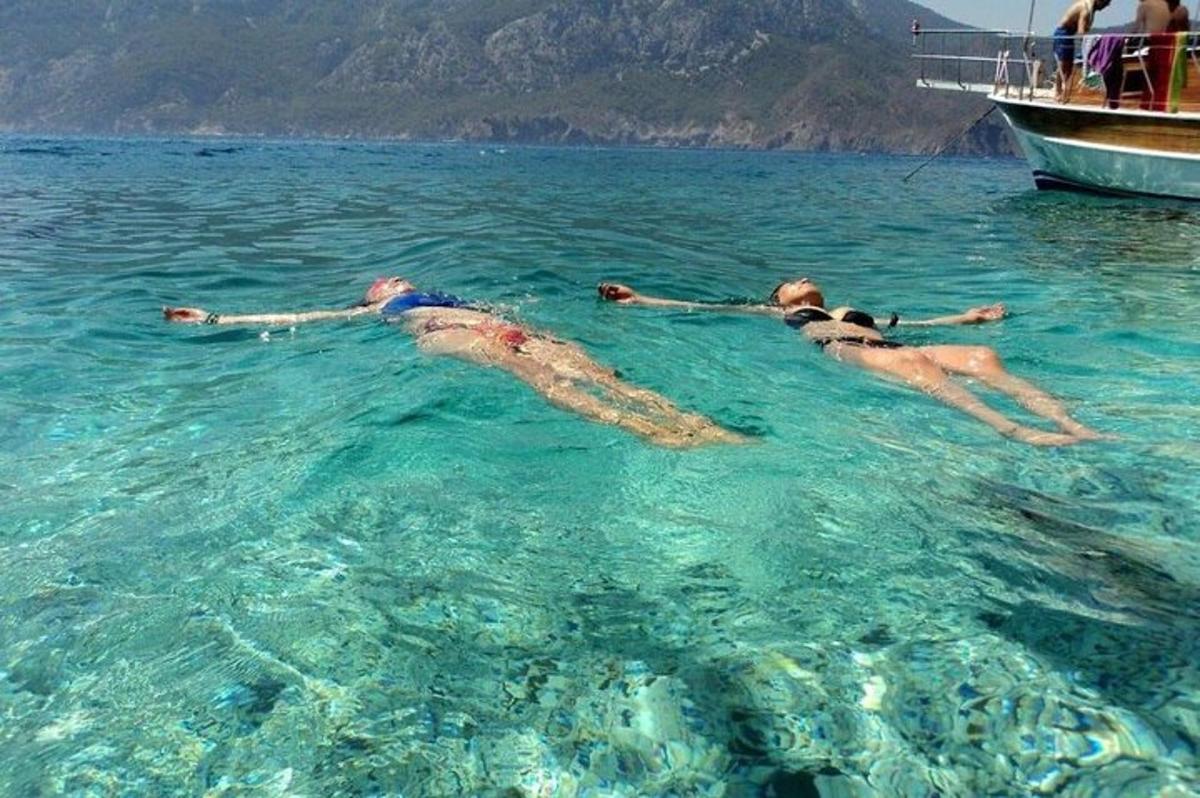 un gruppo di persone che nuotano nell'acqua accanto a una barca