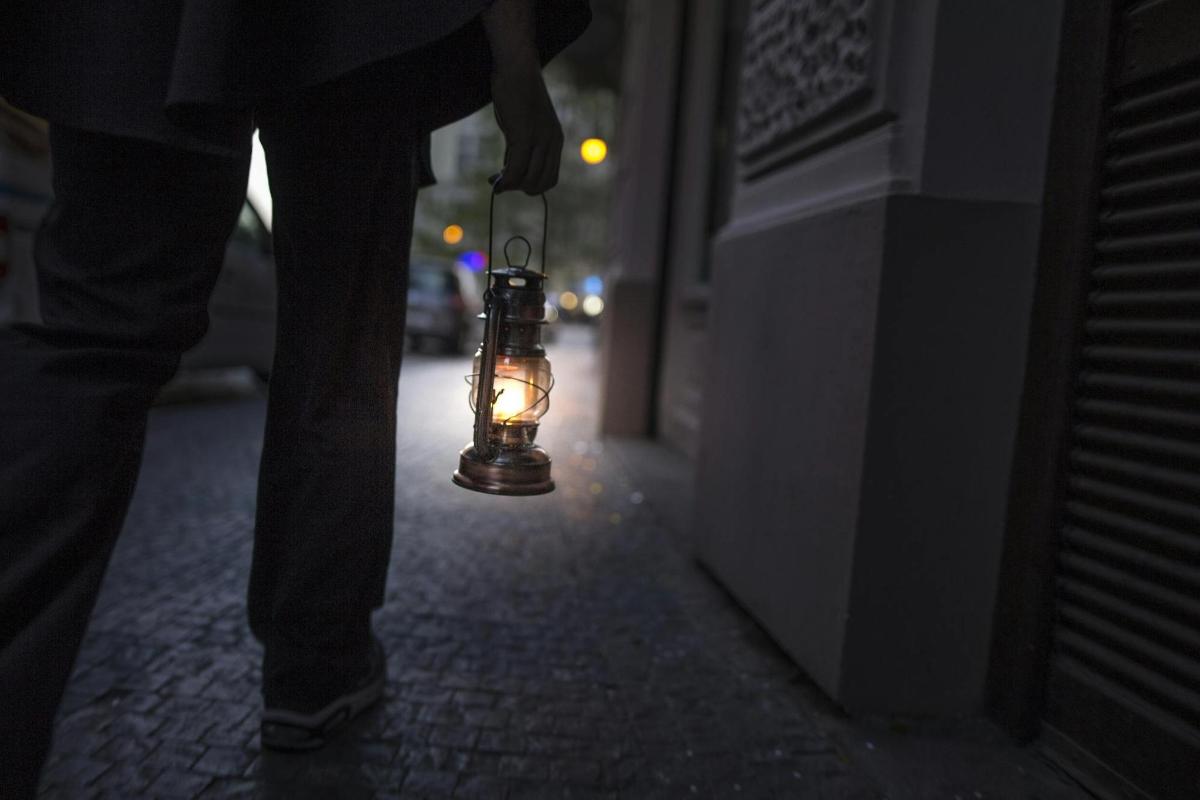 una persona che cammina per strada con una luce in una lanterna