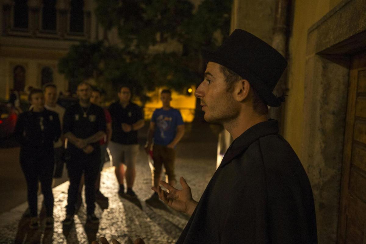 un bărbat purtând o pălărie neagră stând pe o stradă