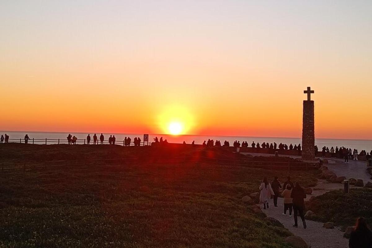 Un grupo de personas caminando por un sendero junto a un faro.