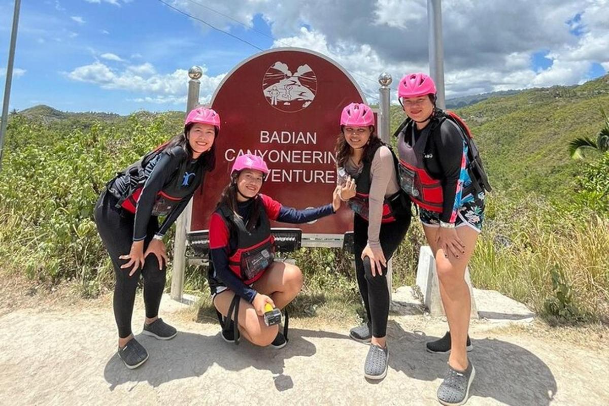 apat na batang babae na nakasuot ng pink na helmet na nakatayo sa harap ng isang karatula