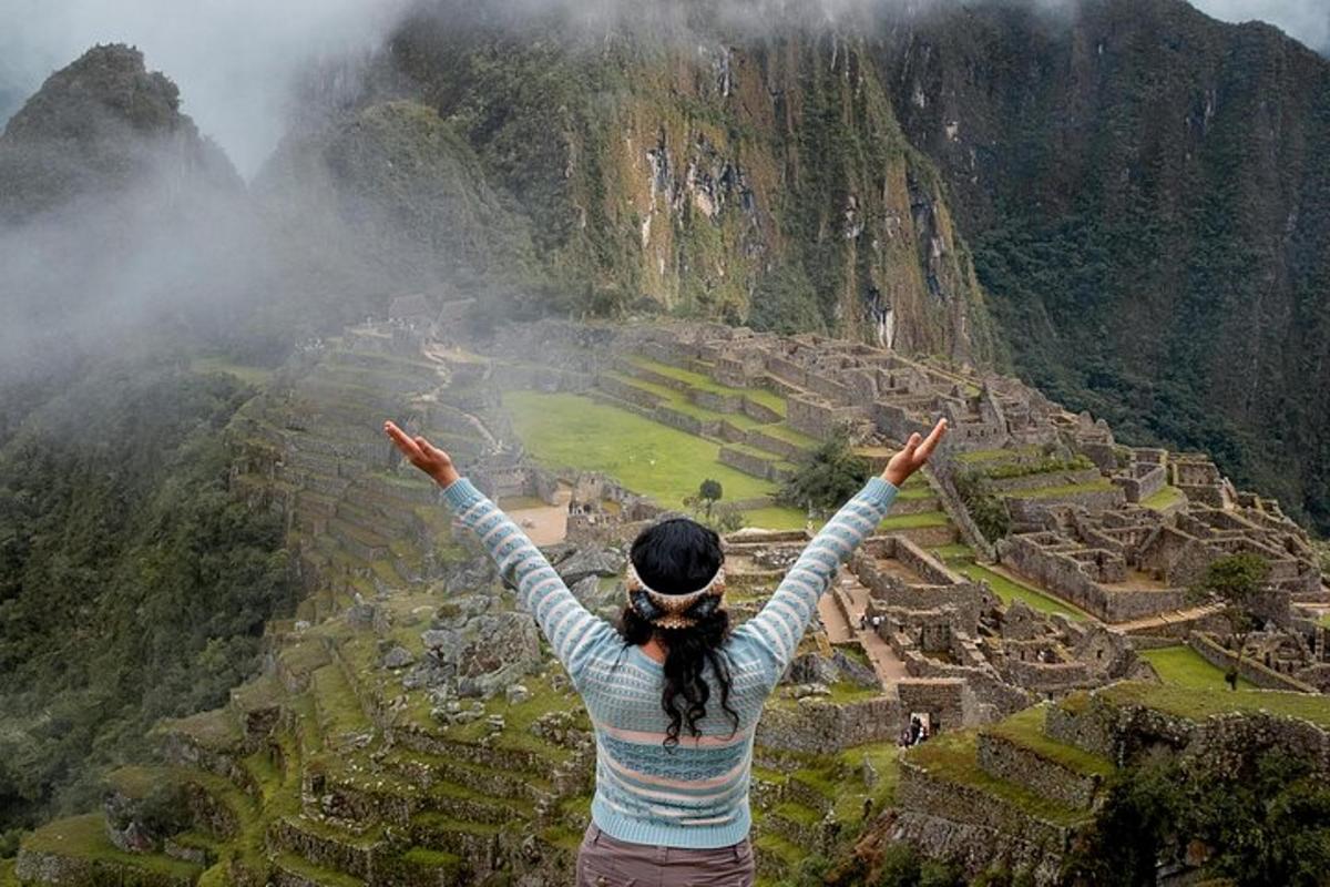 a woman standing on top of a mountain with her arms up