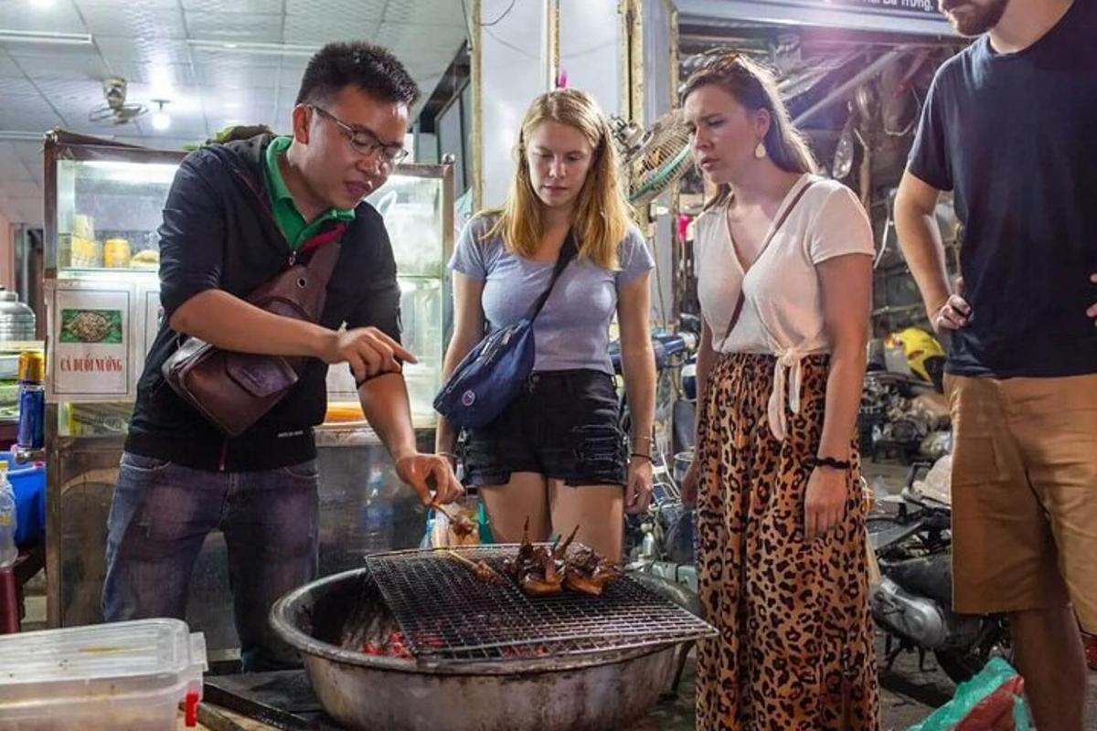 Un grupo de personas de pie alrededor de una parrilla