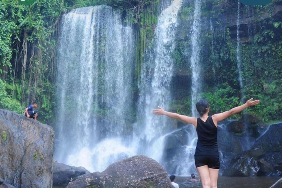 seorang wanita berdiri di hadapan air terjun