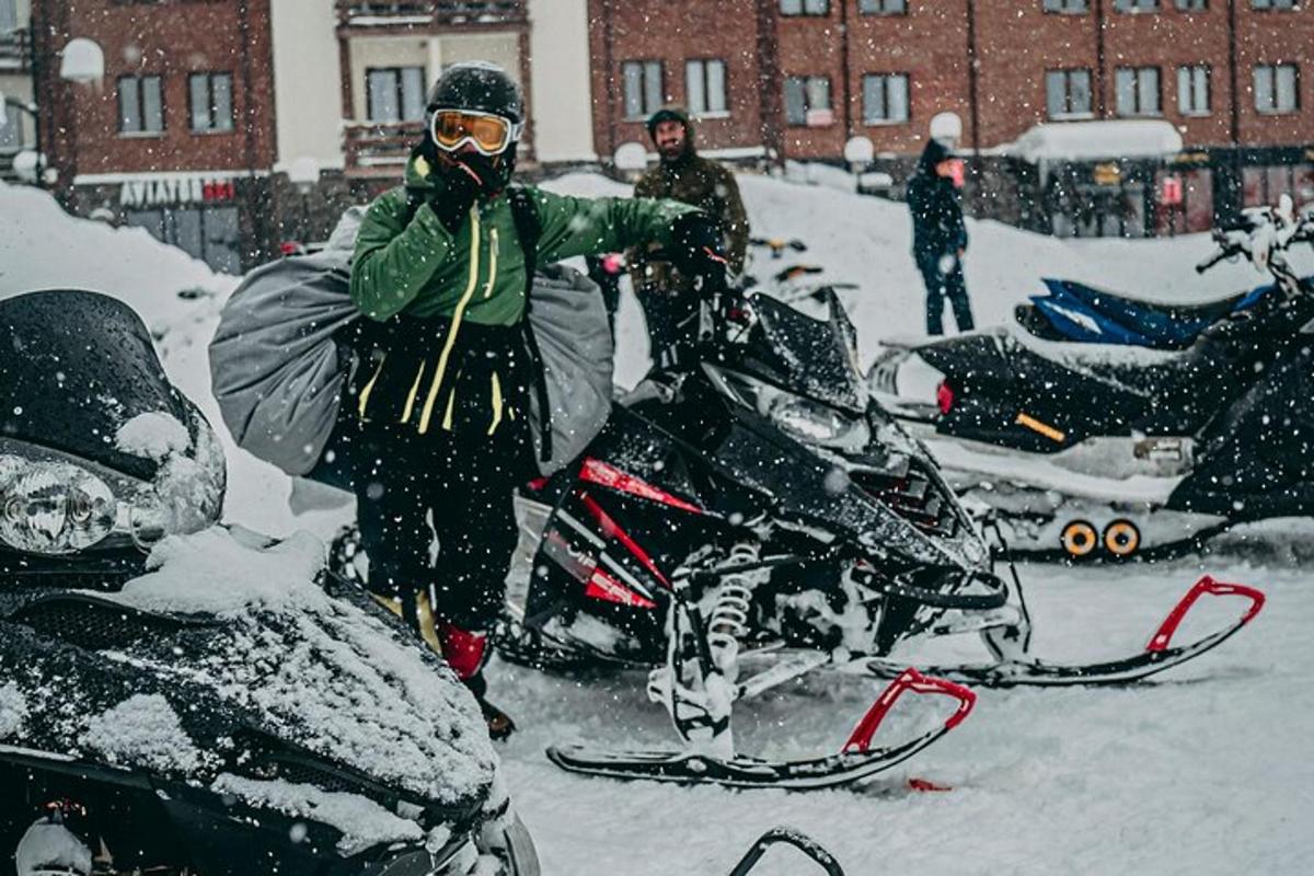 o persoană care stă în zăpadă lângă un snowmobil