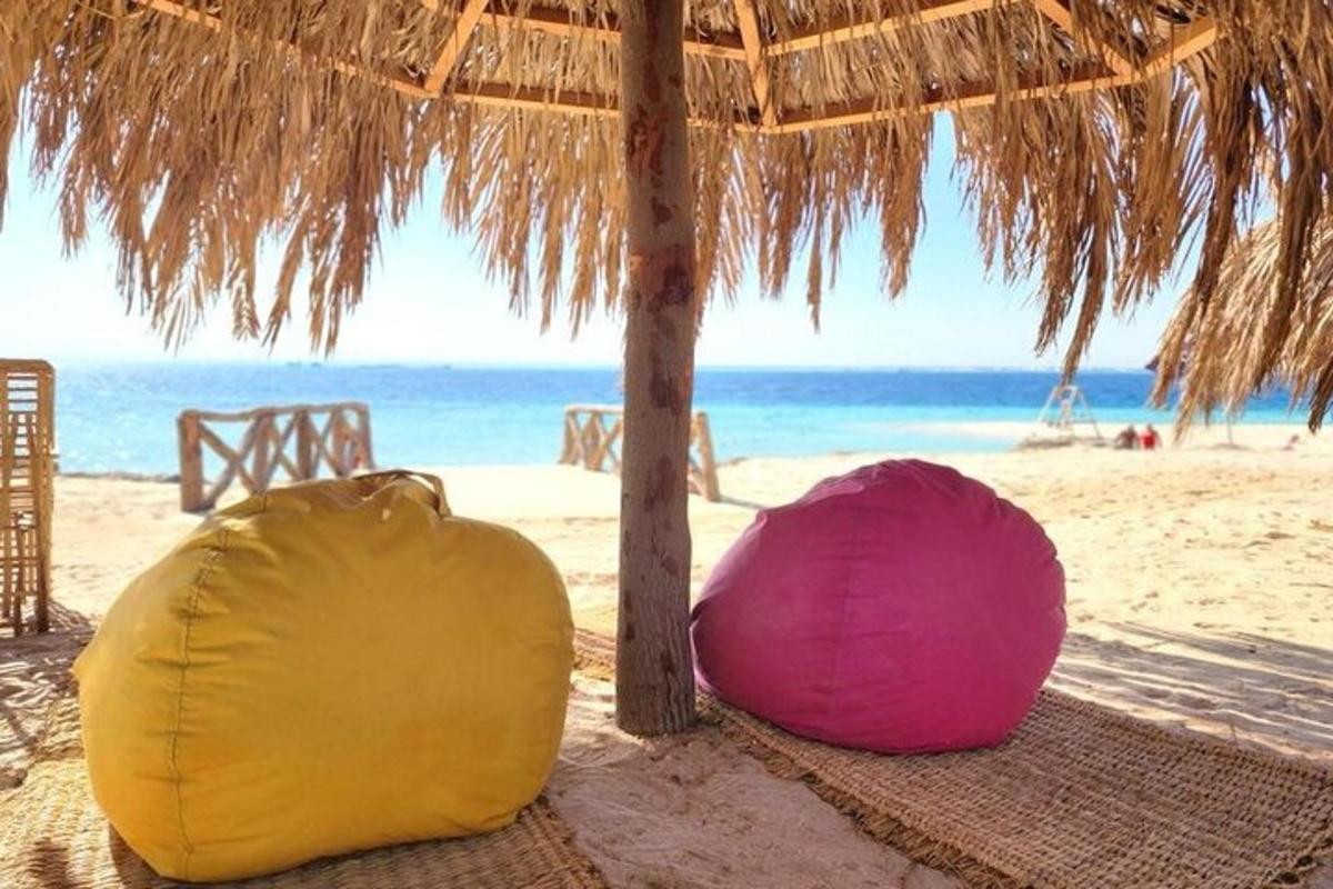to tasker sidder på en strand med en stråparaply