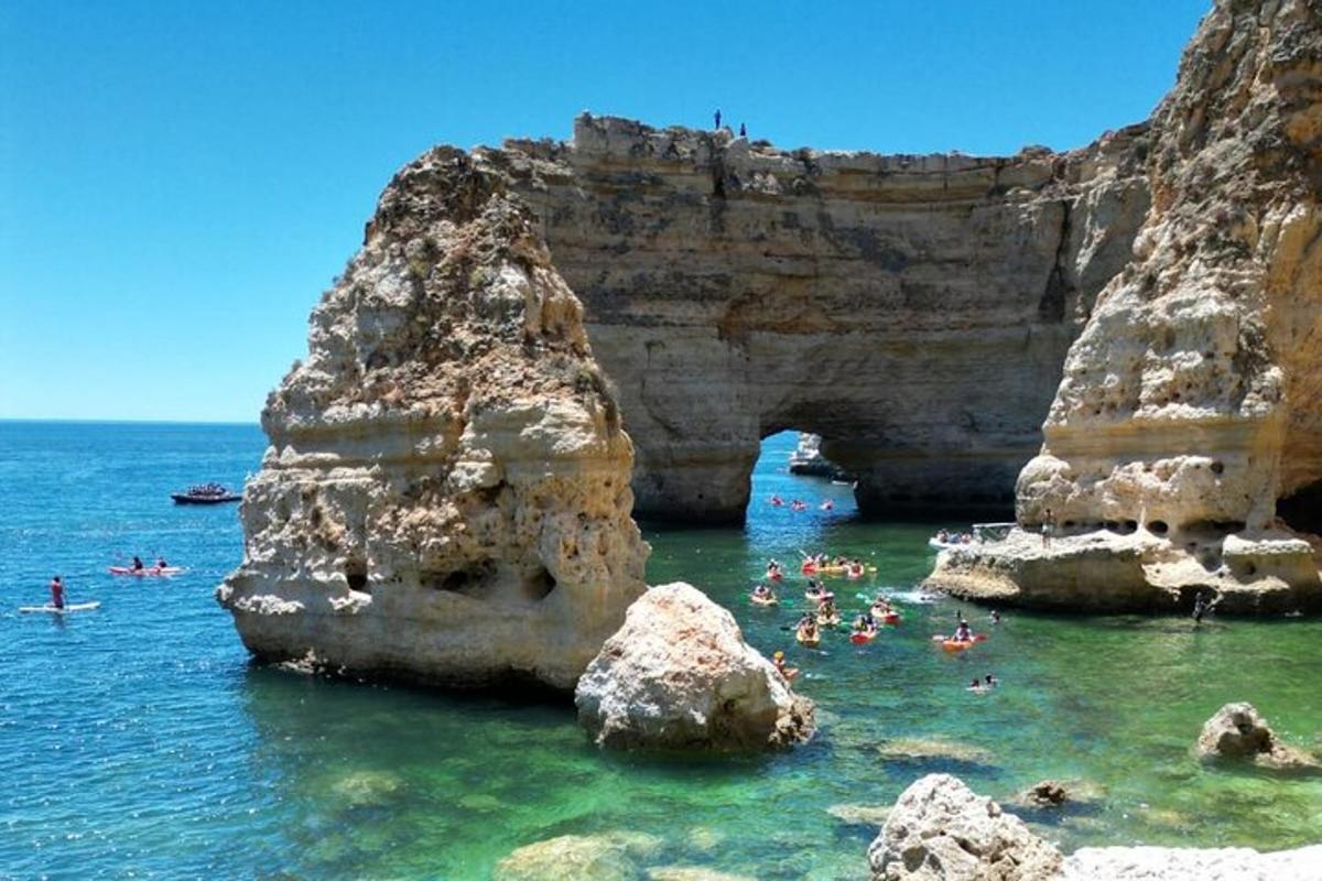 Skupina lidí plave v oceánu poblíž skal