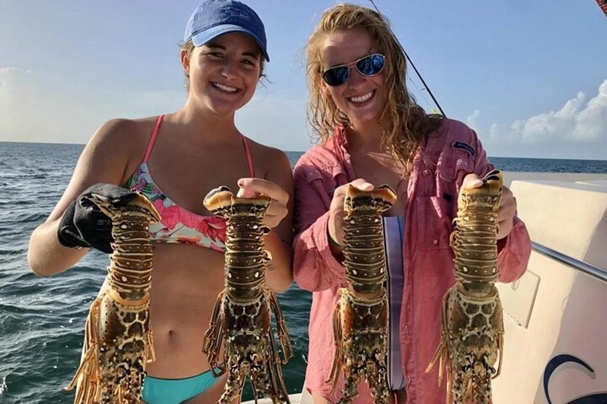 two women on a boat holding up large sea turtles