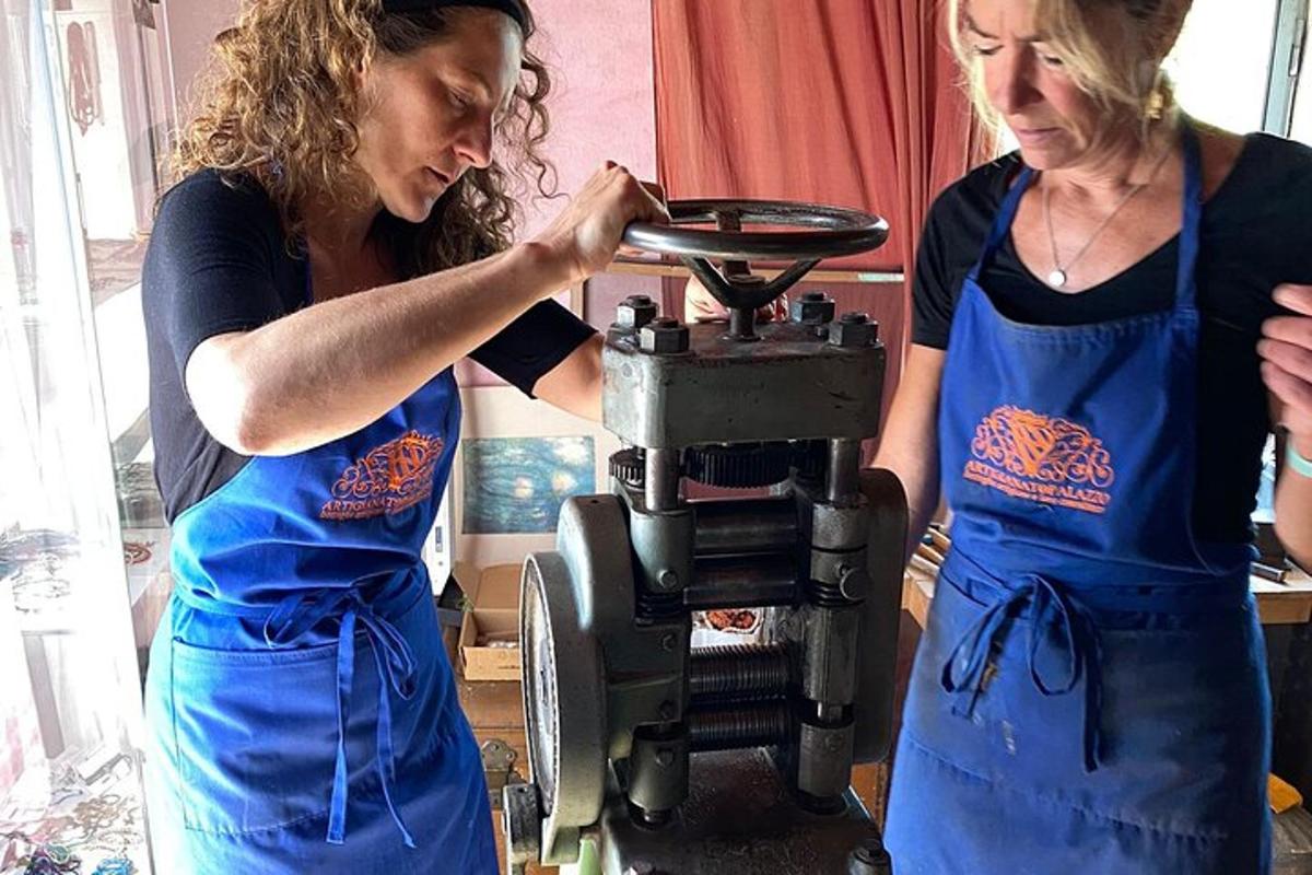 dua wanita memakai apron biru berdiri di sebelah mesin