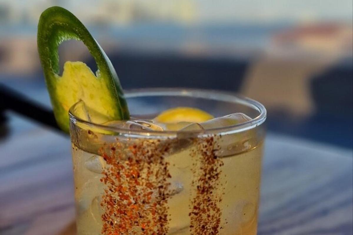 a drink with a pickle in a glass on a table