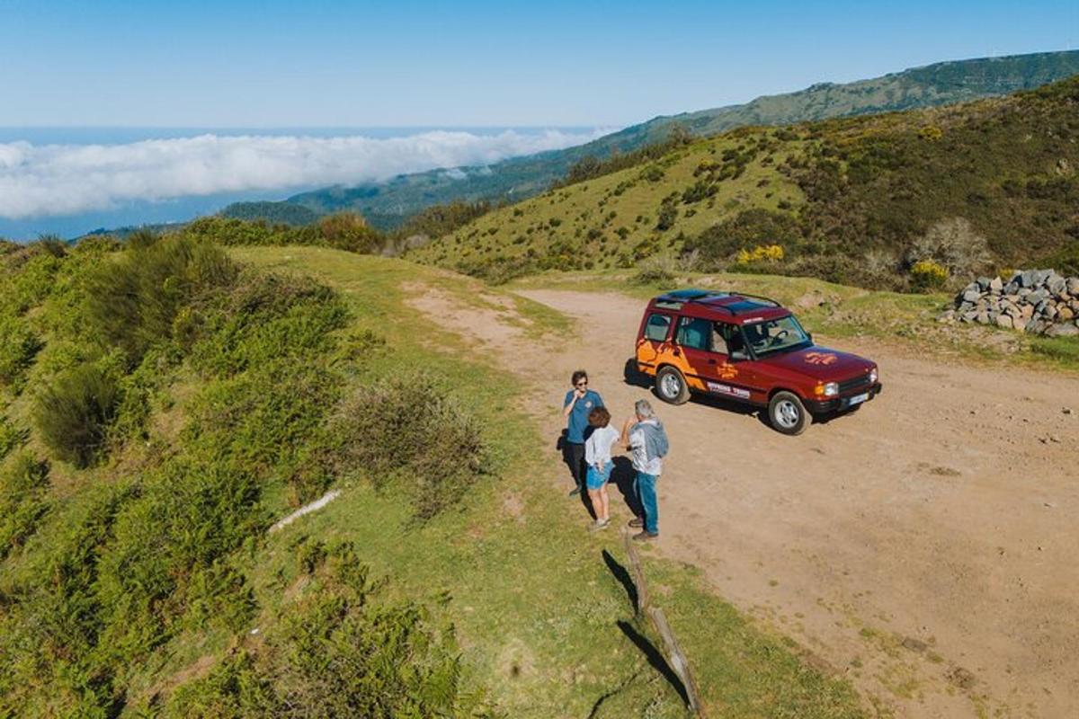 dues persones caminant per un camí de terra al costat d'una furgoneta vermella