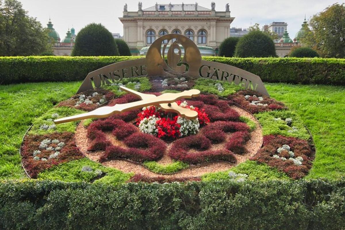 Un reloj de flores en el césped frente a un edificio.