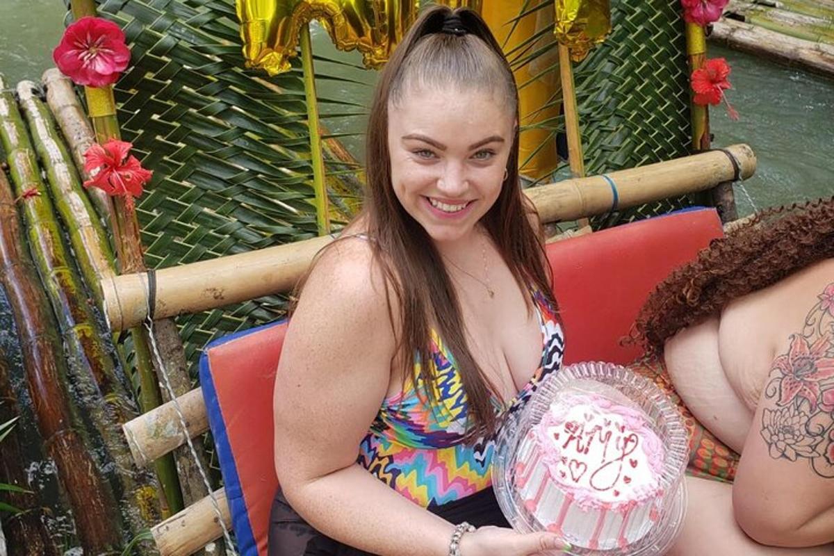 una giovane donna che tiene in mano una torta con la scritta "Compleanno"