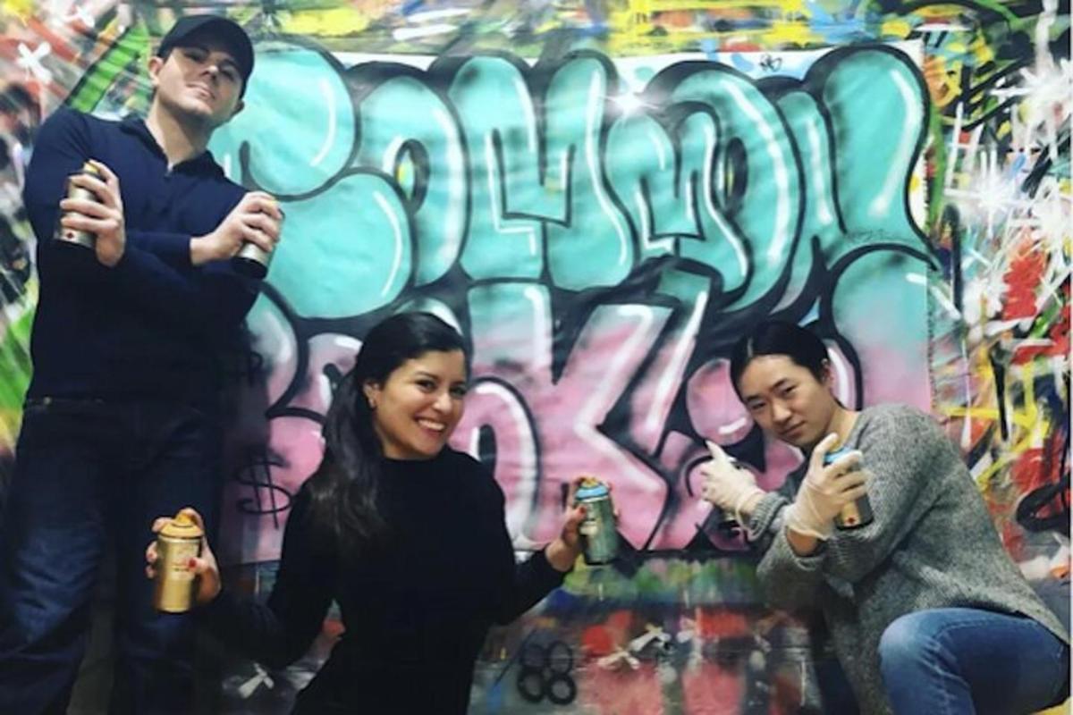 sekumpulan orang berdiri di hadapan dinding dengan grafiti