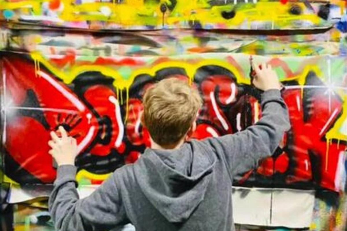 genç bir çocuk duvara grafiti çiziyor