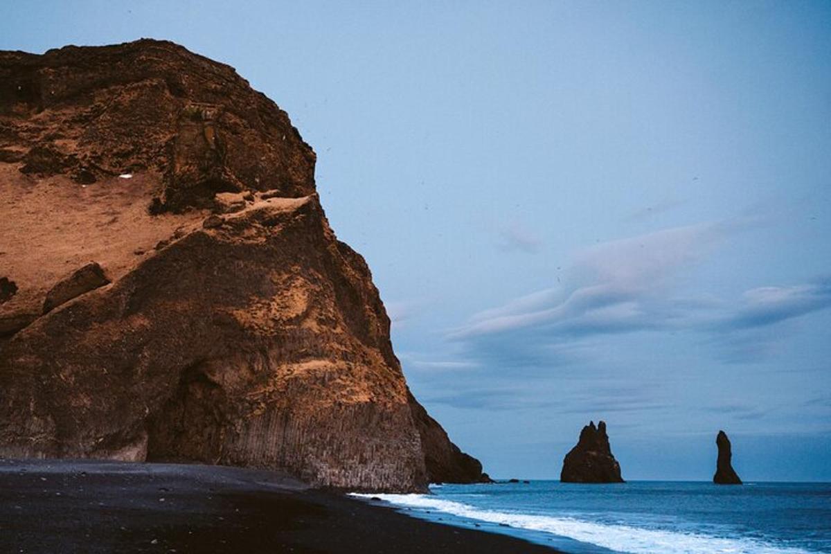 a black beach with a rock formation in the ocean