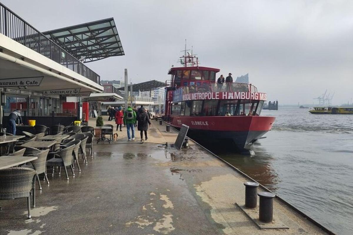 en rød båt ligger til kai ved en brygge med bord og stoler