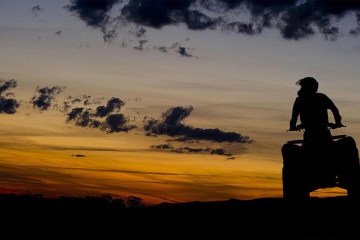 silueta d'una persona conduint una motocicleta a la posta de sol