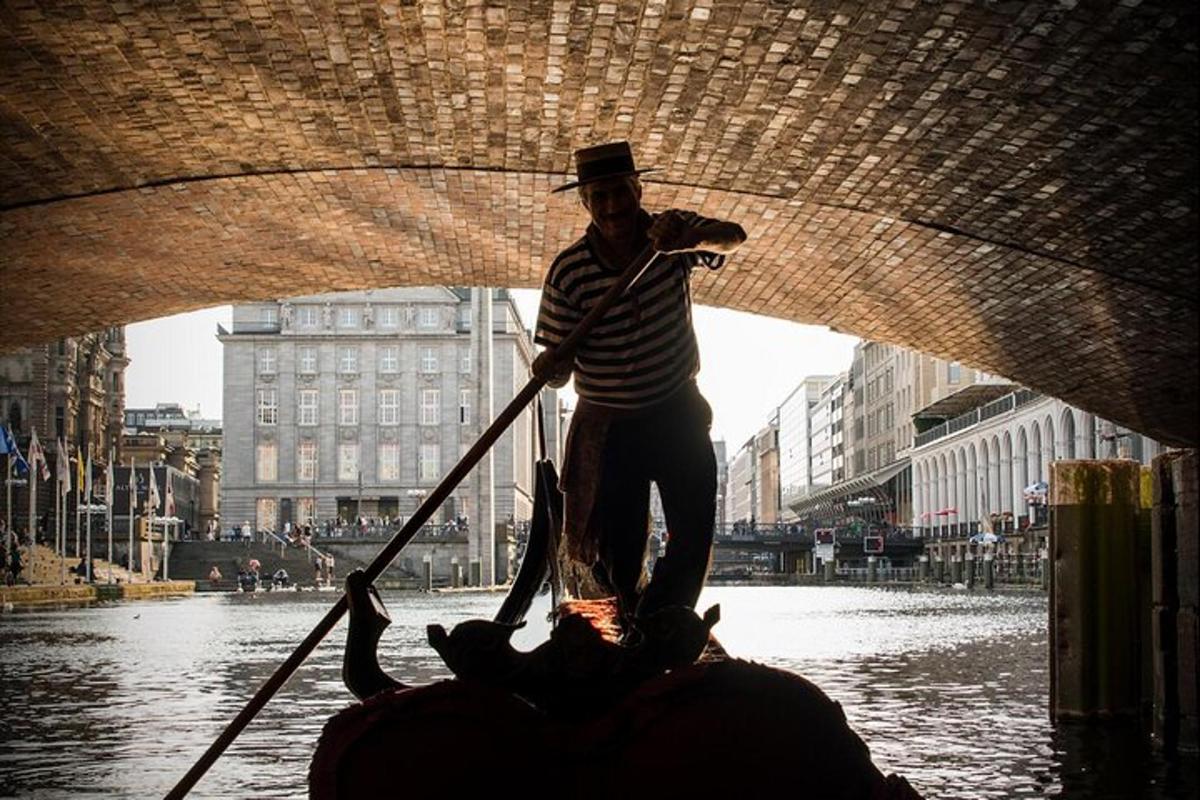 un uomo che rema su una gondola nell'acqua sotto un ponte