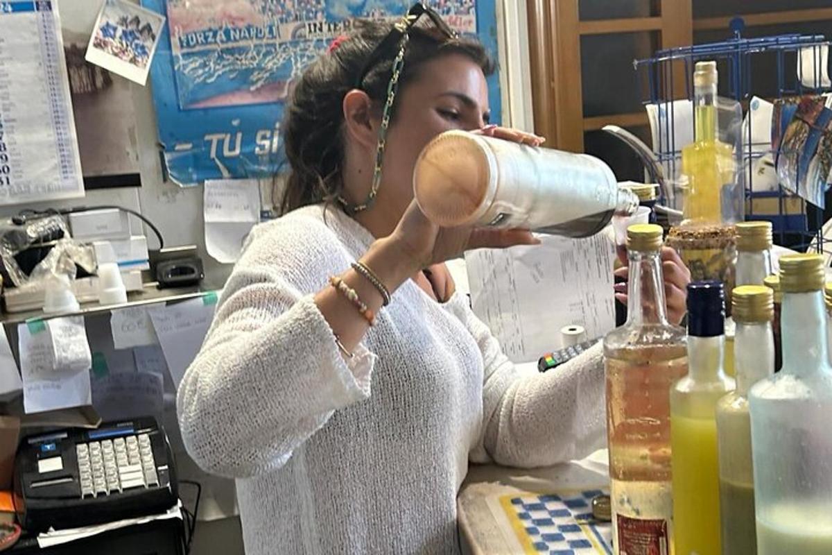 seorang wanita berdiri di kaunter minum dari botol