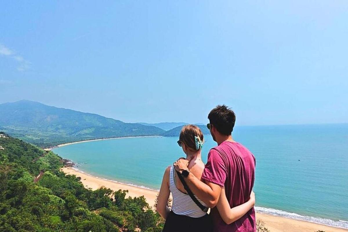 мушкарац и жена стоје на брду са погледом на плажу