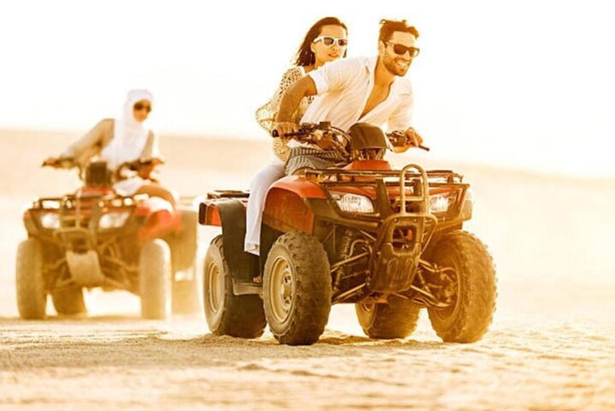 due persone in sella a un quad sulla spiaggia
