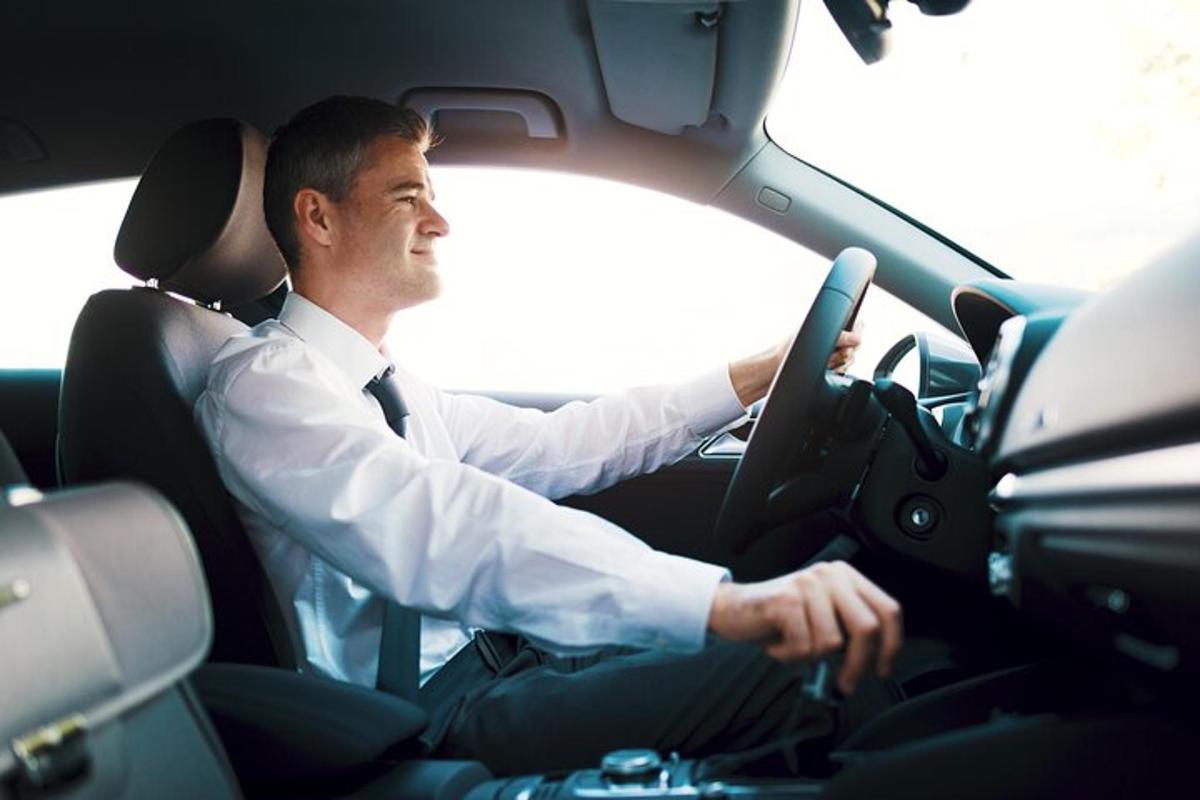 muž řídící auto s rukama na volantu