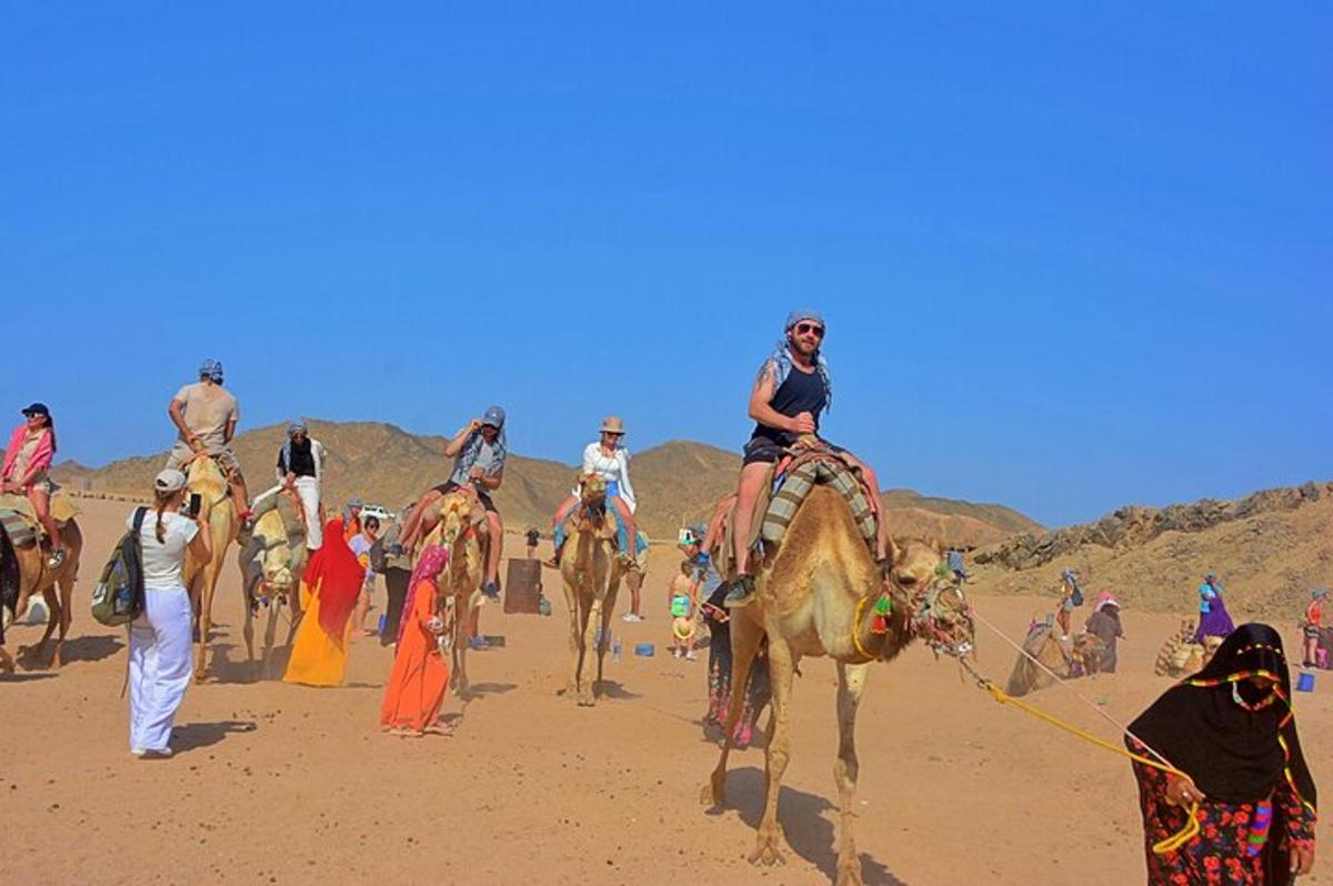 Un grupo de personas montando camellos en una playa.