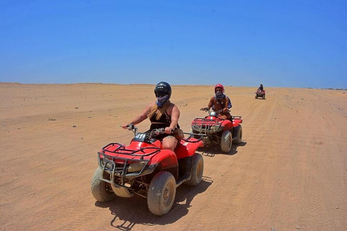 duas pessoas andando de quadriciclo no deserto