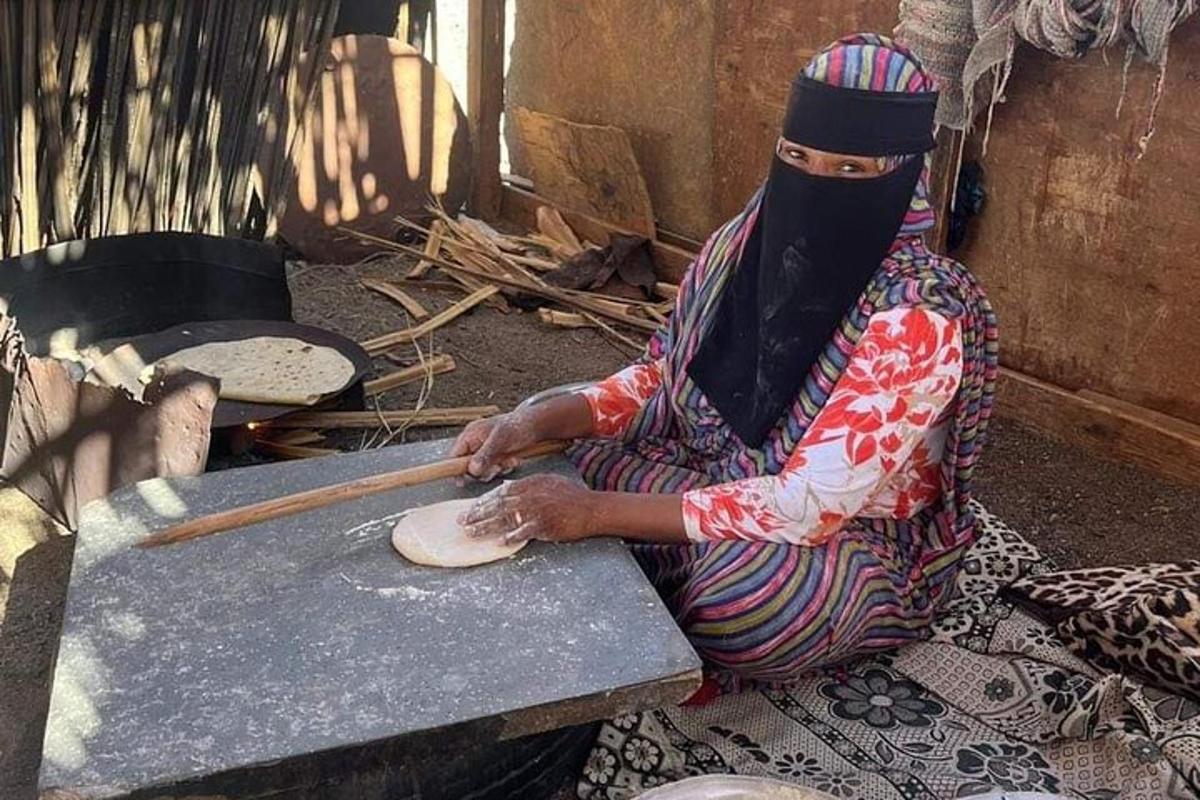 seorang wanita sedang duduk di atas tanah di sebelah ketuhar