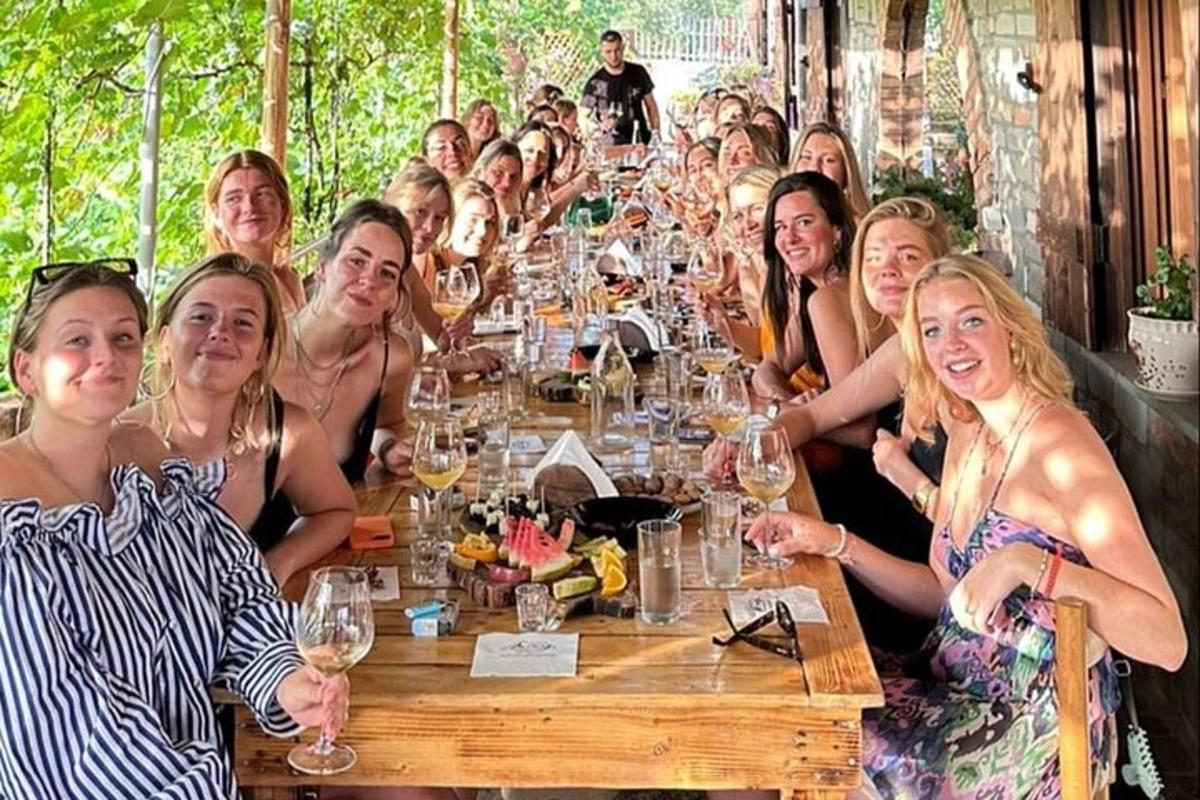 un gruppo di donne sedute attorno a un tavolo con bicchieri di vino