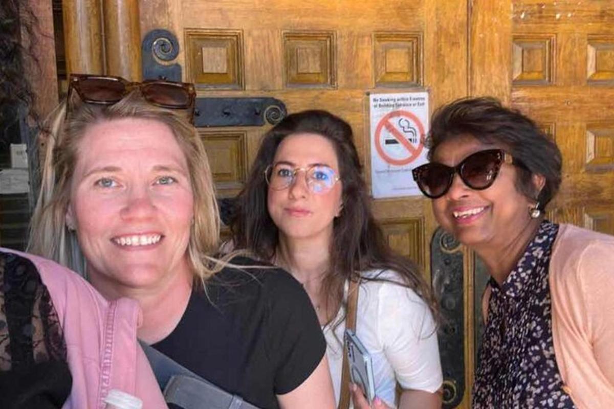 Tres mujeres posando para una foto frente a una puerta
