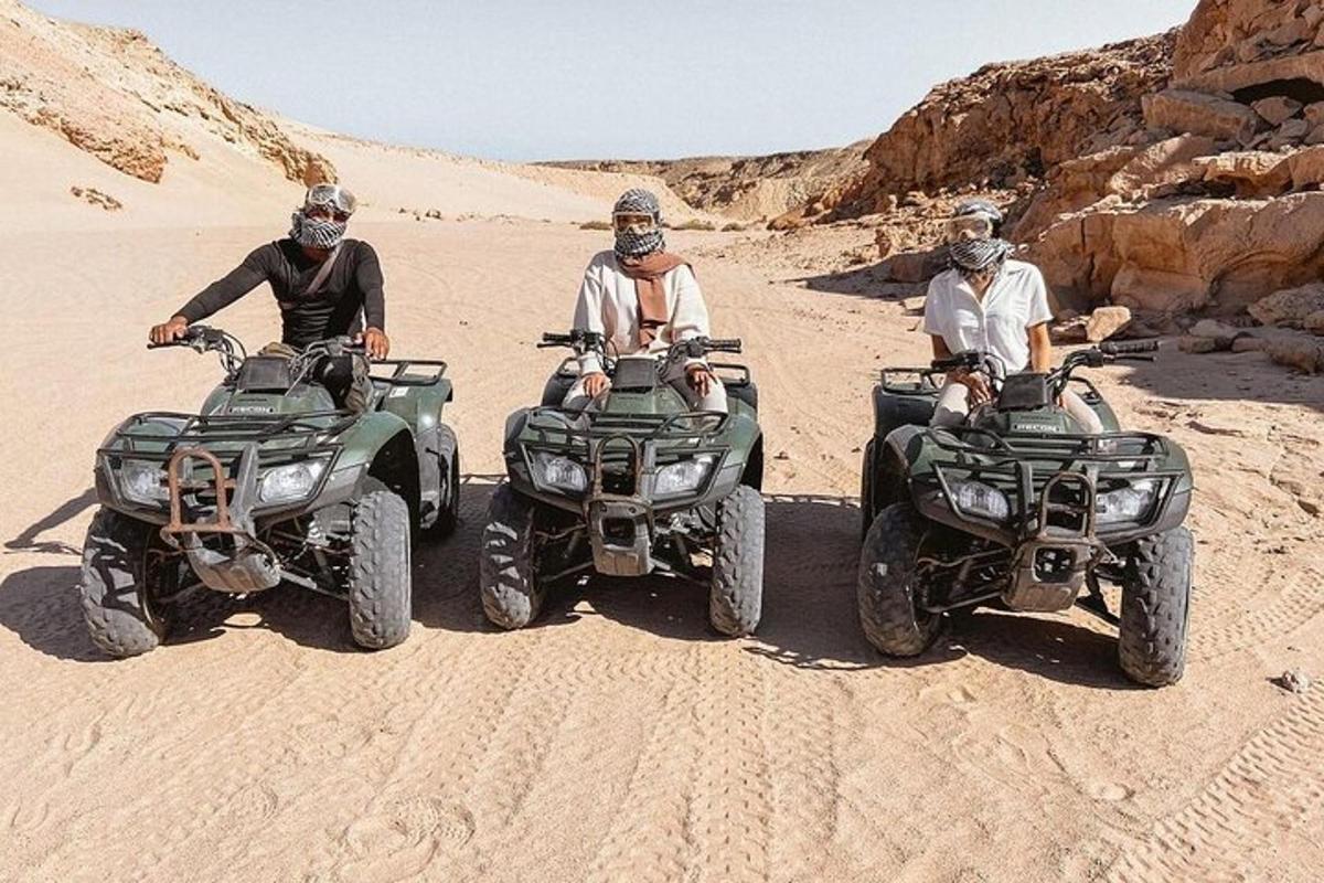 Három ember ül ATV-ken a sivatagban